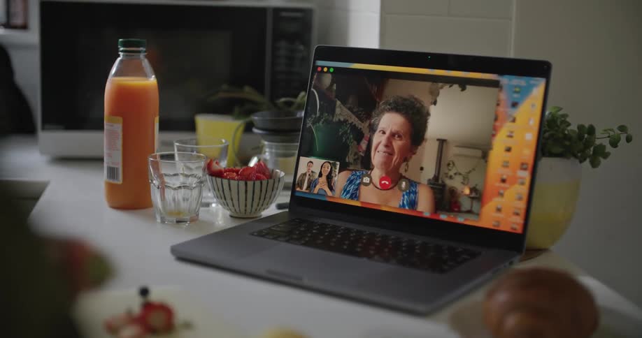 A person cuts fruit during a video call on a laptop