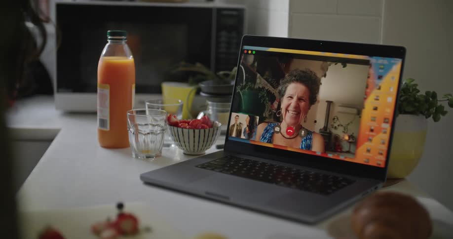 Close up of the screen of a laptop where an happy elderly woman laughs and smile while talking