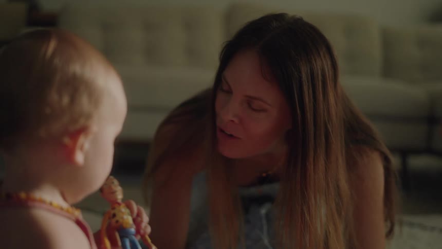 Mother kneeling on the floor of the living room plays with her baby girl