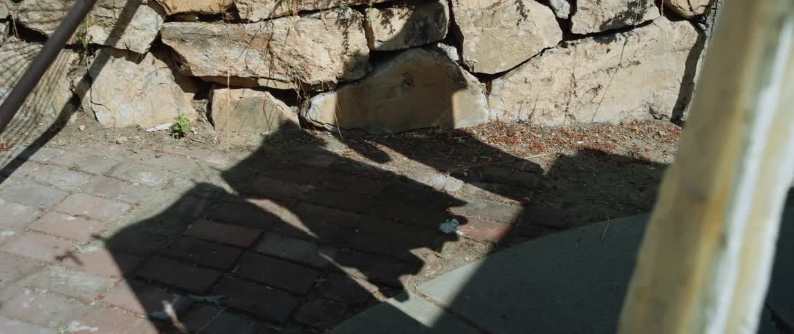Shadow on the ground of clothes hanging out to dry on clothesline