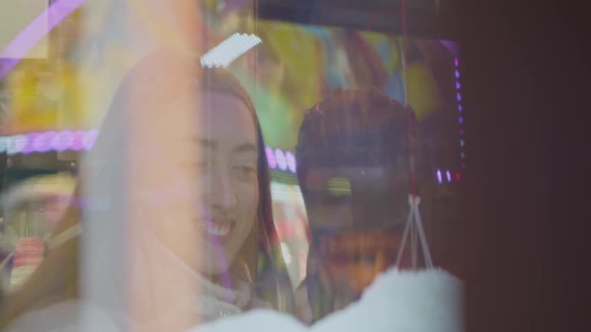 A young man and woman smile and laugh as the play a game at a carnival