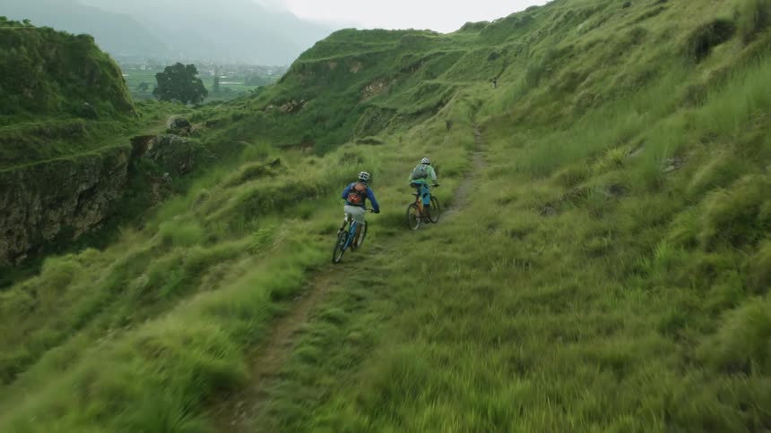 Cyclists Navigate Grassy Slope and Narrow Path