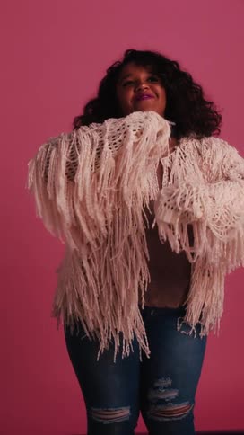 Chubby black woman dances on a pink background