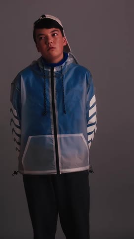 A very bored looking boy stands inside