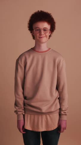 A teenager dressed in pink stands in front of a matching wall and smiles