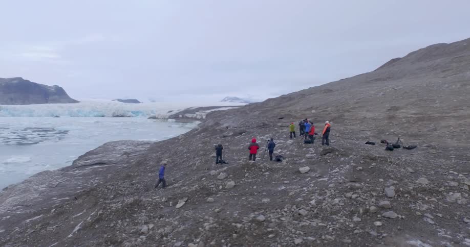 People are in a group by the ice filled water