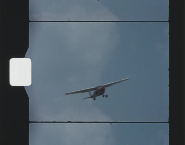 A vintage film shows an airplane soaring through the sky