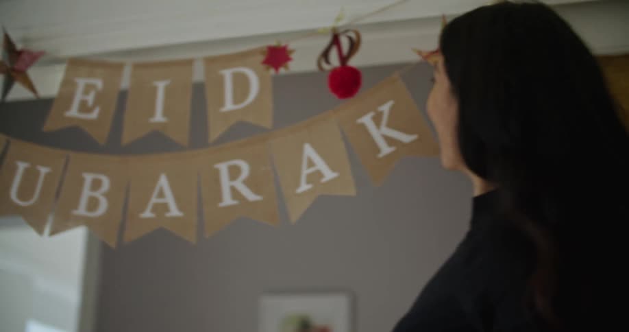 A woman smiles brightly as she sees a decoration hanging indoors