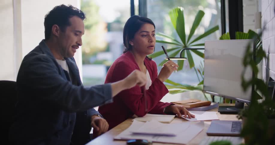 Two coworkers are talking and looking at a computer