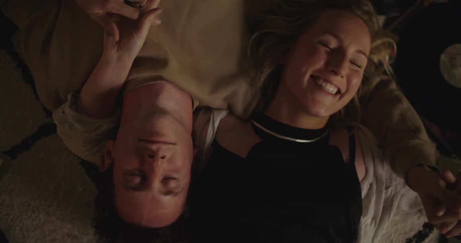 A woman kisses her partner on the cheek while lying in bed