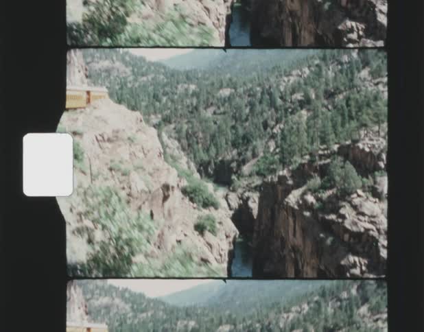 A canyon in a mountain while a train goes around the mountain