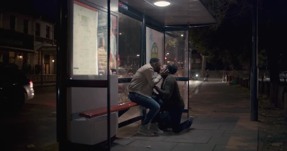 A man proposing to another man at a bus stop