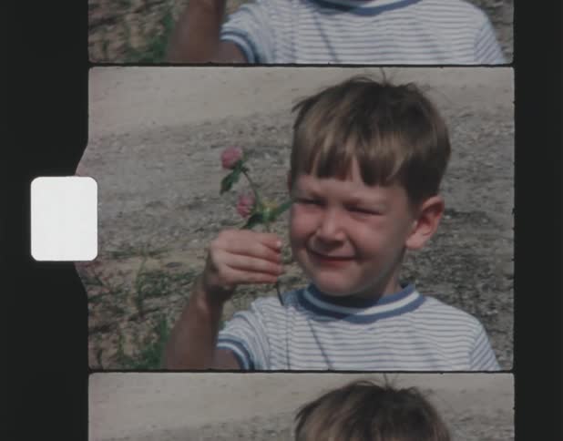 A boy is holding up a flower