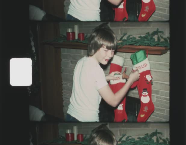 A boy removes his christmas stocking from the fireplace mantel