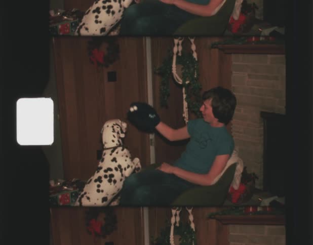 A man is playing with his dog in the living room