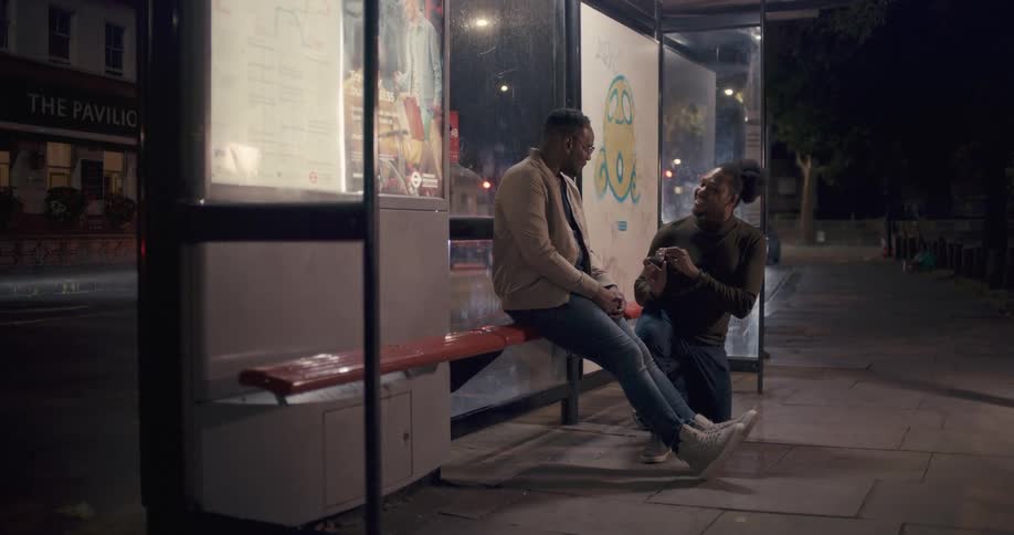 A man proposes to his boyfriend at a bus stop