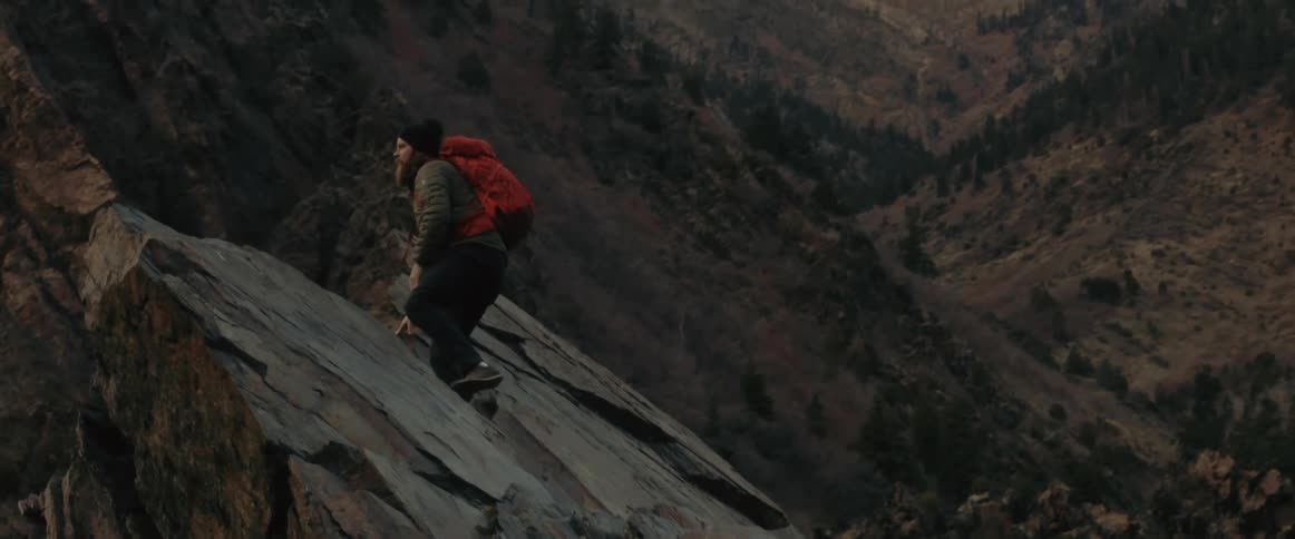 A man is climbing up a rock summit