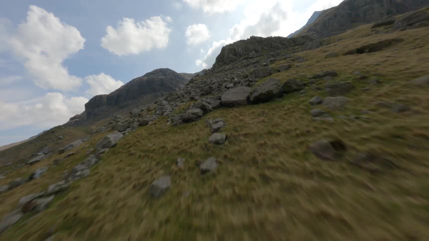 Drone flying close to the ground star wars style over rough terrain in a mountainous area