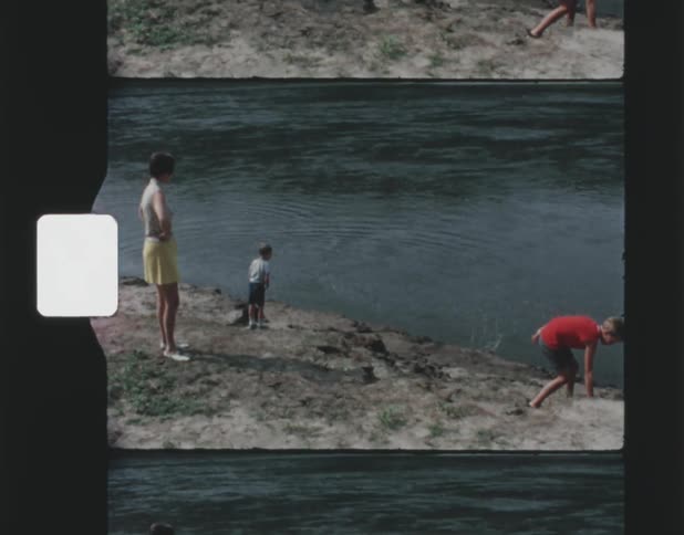 A woman watches as her sons throw rocks in the water