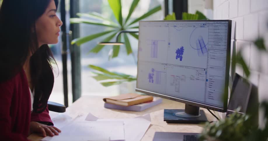 A woman is sitting at her computer desk during midday