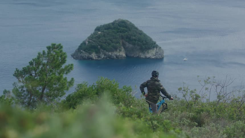 Man is sitting on his bike by the ocean coast