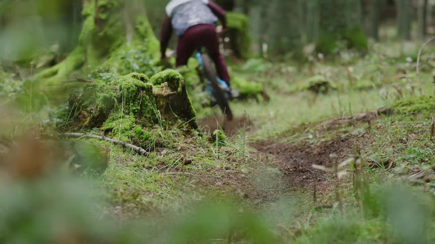 A man rides a bicycle down a dirt trail in the woods