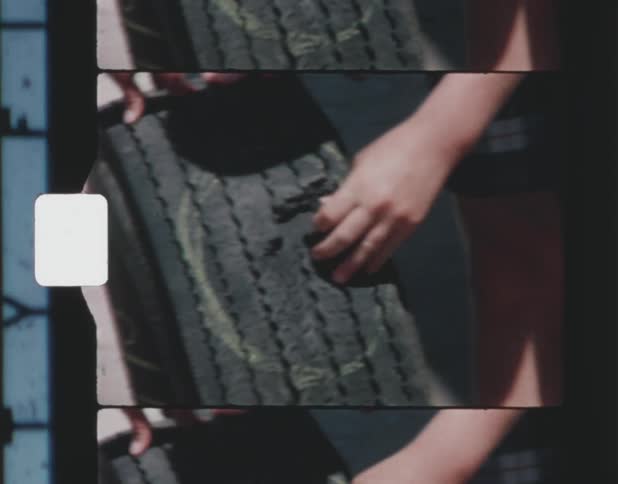 Kids handle ruptured tire while standing outdoors on pavement