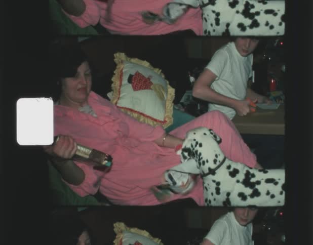 A mother and son open christmas presents as their excited dog looks on