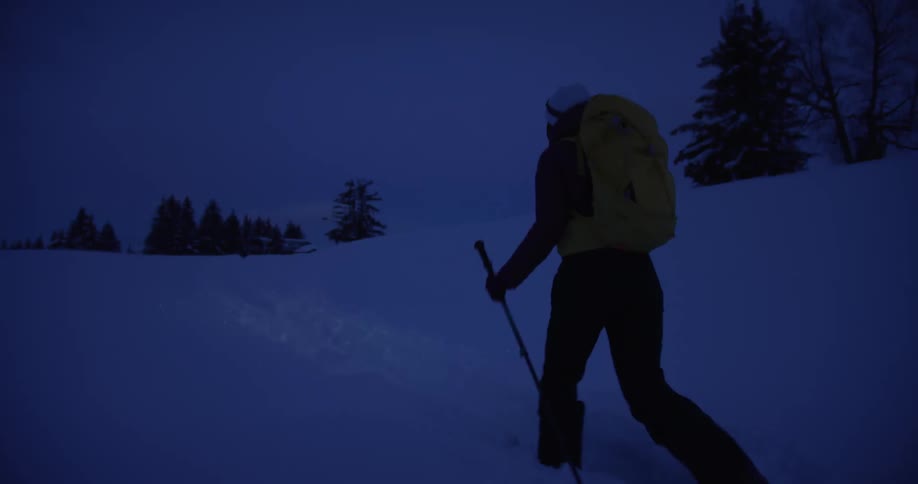 Person moves across snow crossing country on skis at night during winter