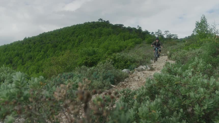 A man rides on a bicycle down a hillside at a very fast speed