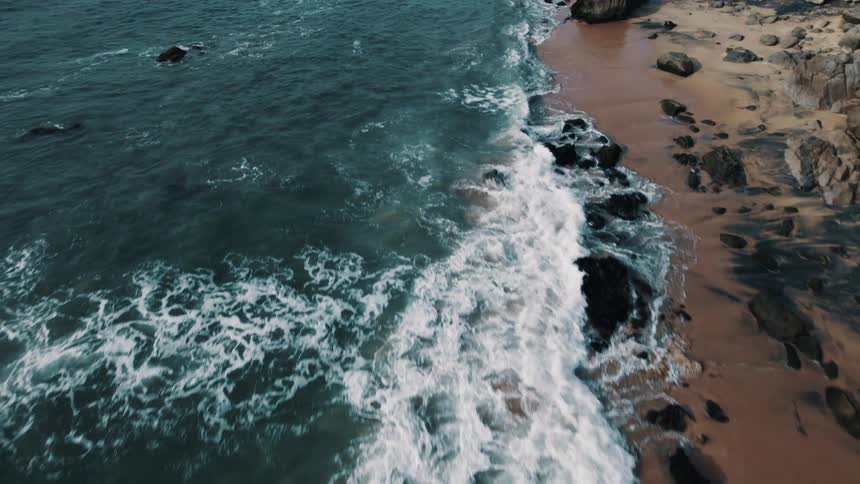 Aerial view of ocean waves moving towards the beach coast