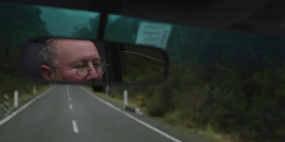 A man is reflected in the rearview mirror