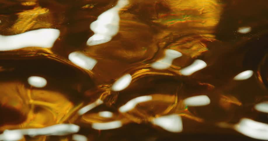 A close up of a gold clear oily liquid surface