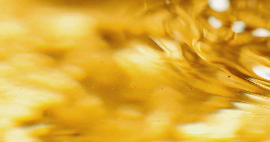 Light shines on ripples moving across the surface of a golden liquid