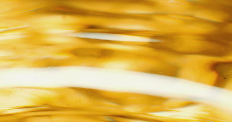 A close up of a gold clear liquid with ripples on the surface