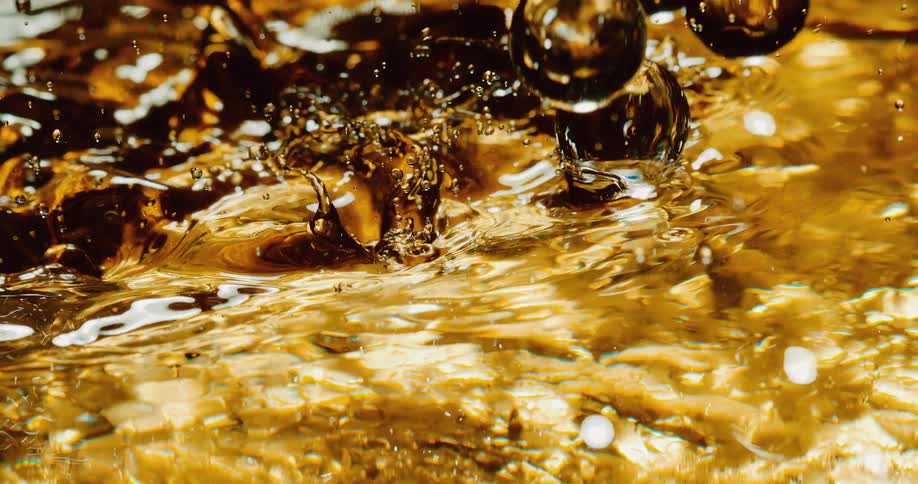 Drops of liquid splash into a pool bottomed by gold