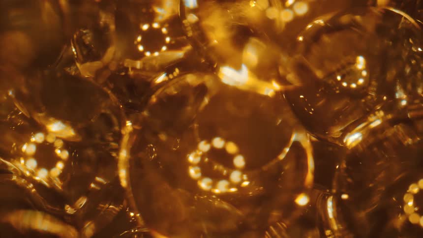 A gold clear liquid with bubbles in it and reflections cast off it