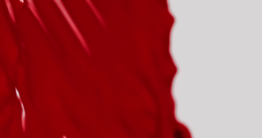 A thick red liquid is dripping as droplet spheres roll over the wet surface as they fall