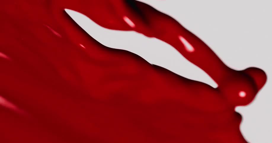 A close up of red paint being poured as it flows out creating ripples