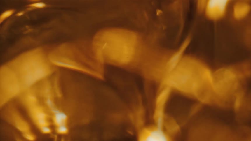 A close up of a clear gold liquid moving around in droplets