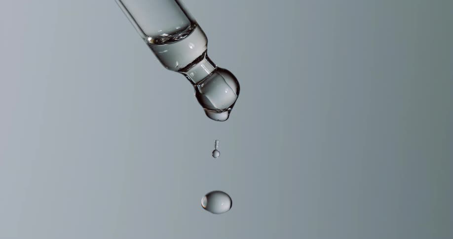 A single droplet of liquid drips off of the tip of a glass probe
