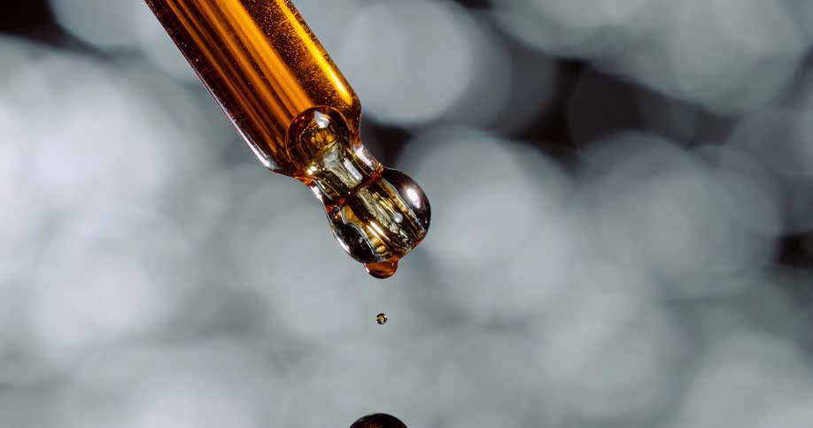 Amber syrup falls from dropper and a bubblemoves up center of dropper
