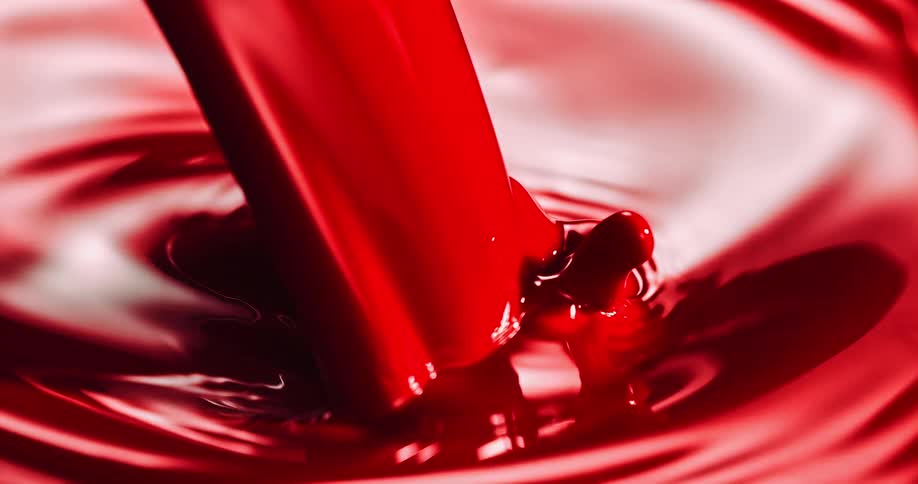 Crimson fluid splashes onto surface of same liquid creating ripples