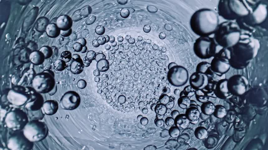 Abstract close up of glass with etchings water and bubbles rising in a spiral motion