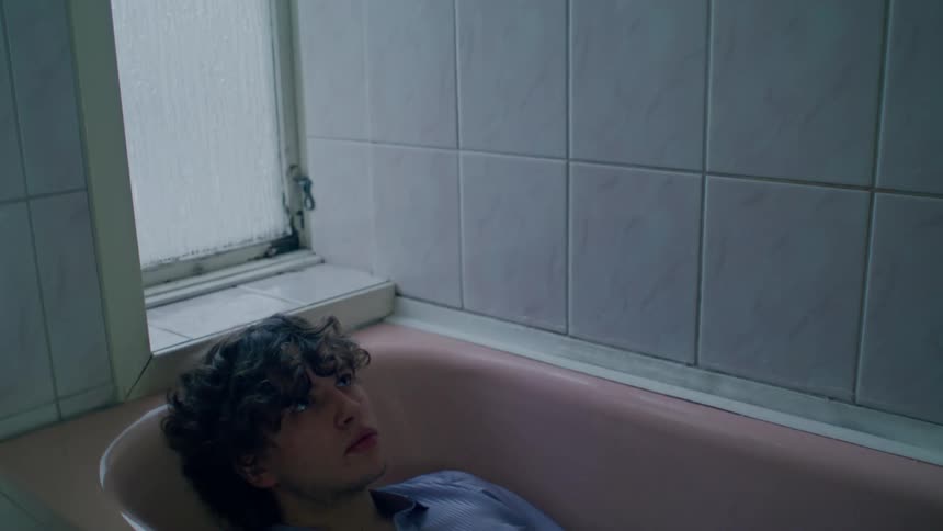 A man lies in an empty bathtub