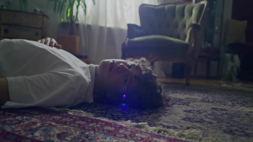 A man poses while lying on a rug at home