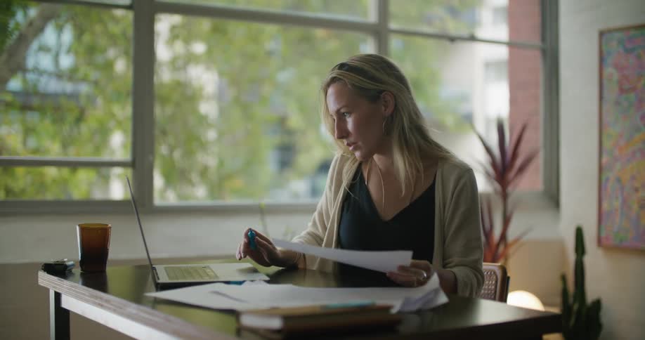 Woman sitting at table highlights paperwork