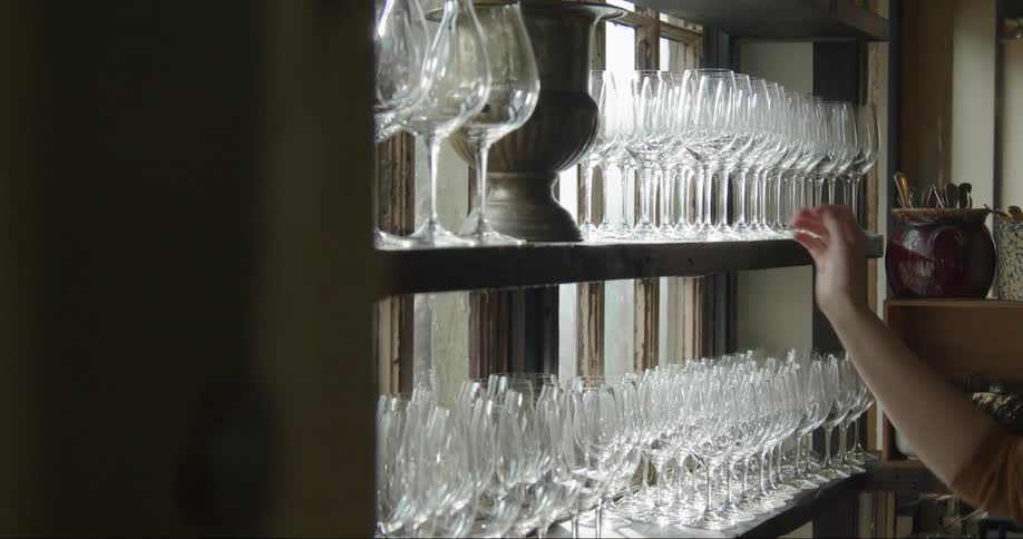 A restaurant worker puts the wine glass on the shelf in a retaurant