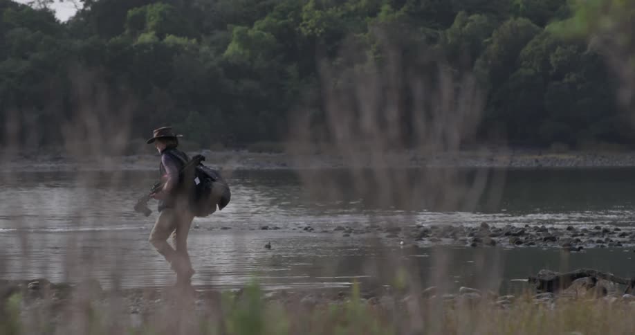 A person is hiking along a stream carrying a camera