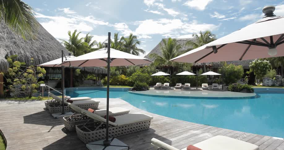 A resort has a large pool with lounge seats and umbrellas